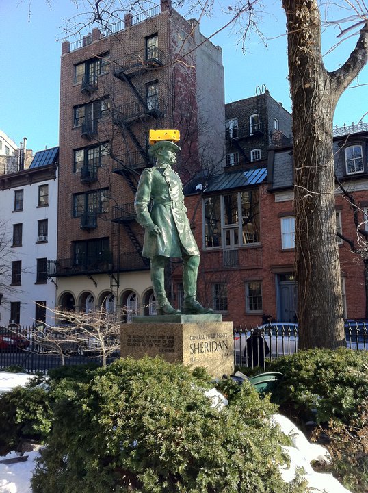 Statue in NYC with a cheesehead on it